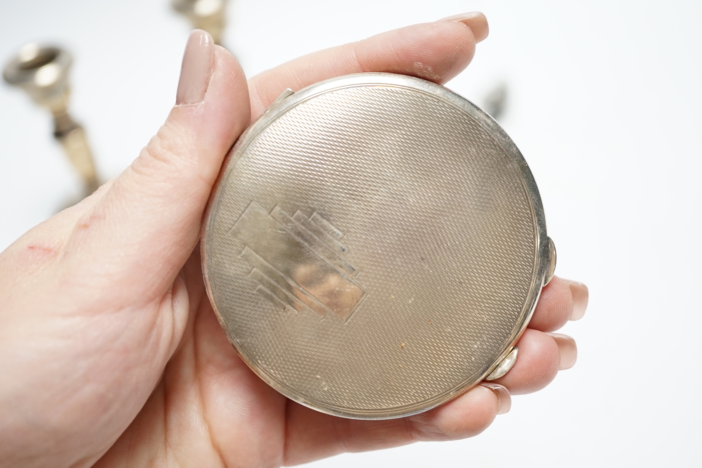 Three silver compacts including one enamelled, a pair of silver mounted dwarf candlesticks, 10.2cm and two other items.